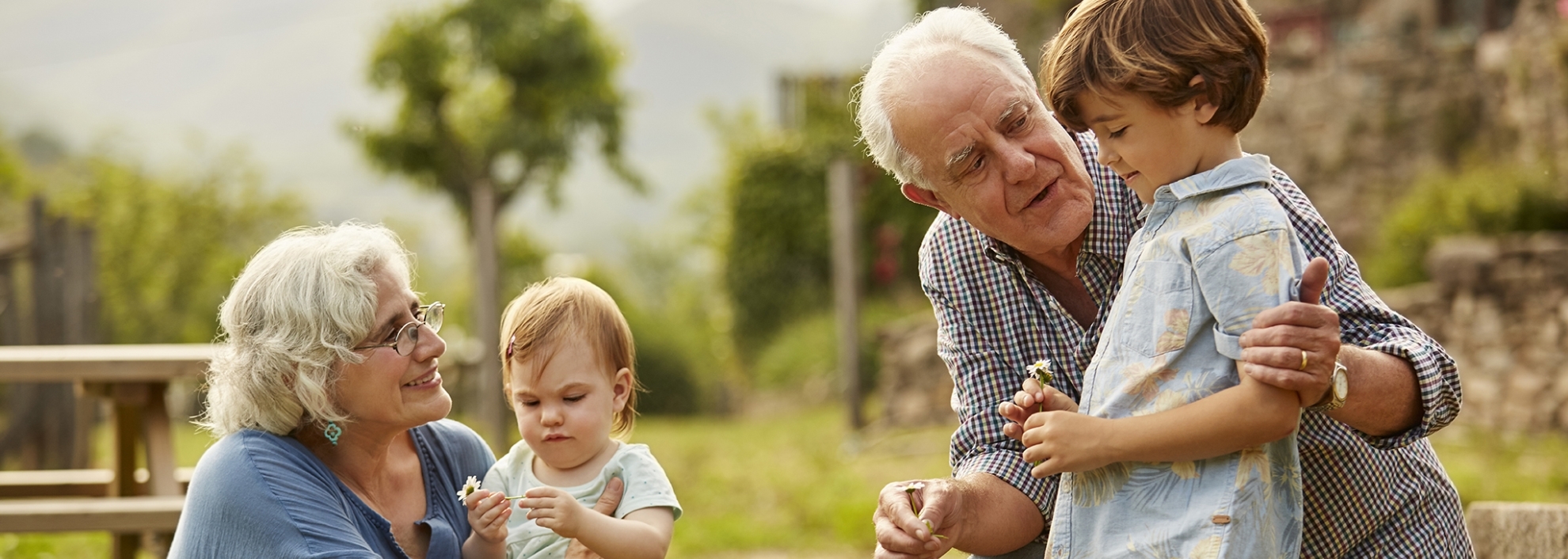 Grandparents talking to children. Family having leisure time in yard. They are wearing casuals.